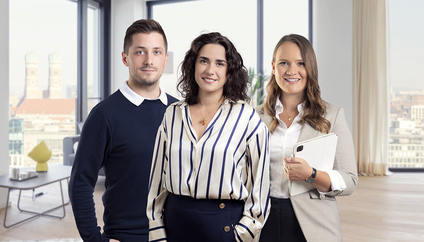Felix Hensel, Doris Palmiero und Lisa Hessner vom Mr.Lodge Team in einem modern möblierten Apartment mit Blick auf die Münchner Frauenkirche – Experten für möblierte Vermietung und Immobilienverkauf in München.