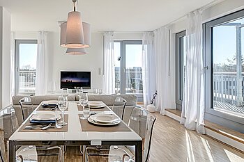 Zu sehen ist der Essbereich einer modernen Wohnung mit bodentiefen Fenstern.