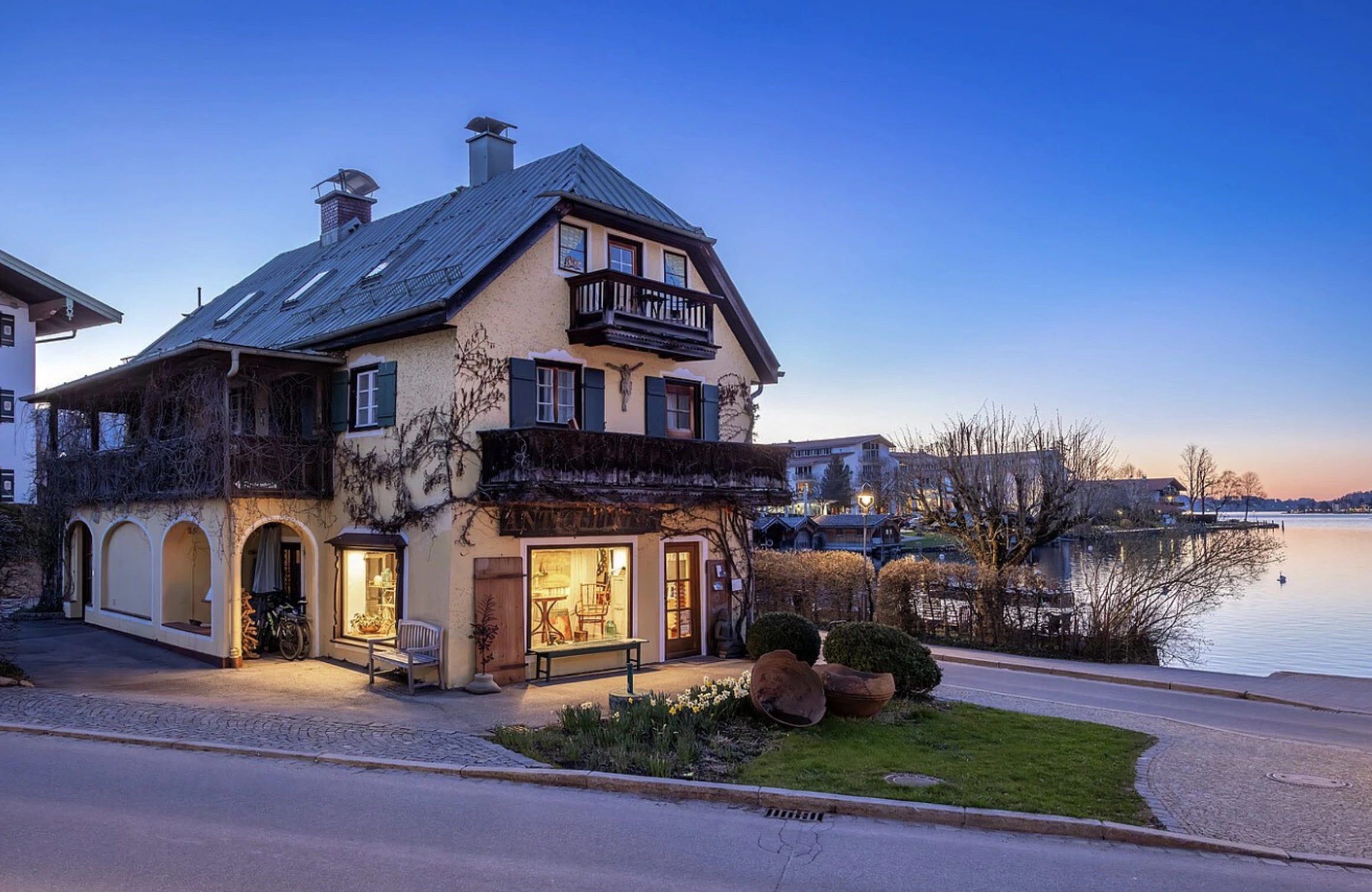 Historisches Landhaus mit Erkern und Holzbalkonen direkt am Ufer des Tegernsees in der Abenddämmerung